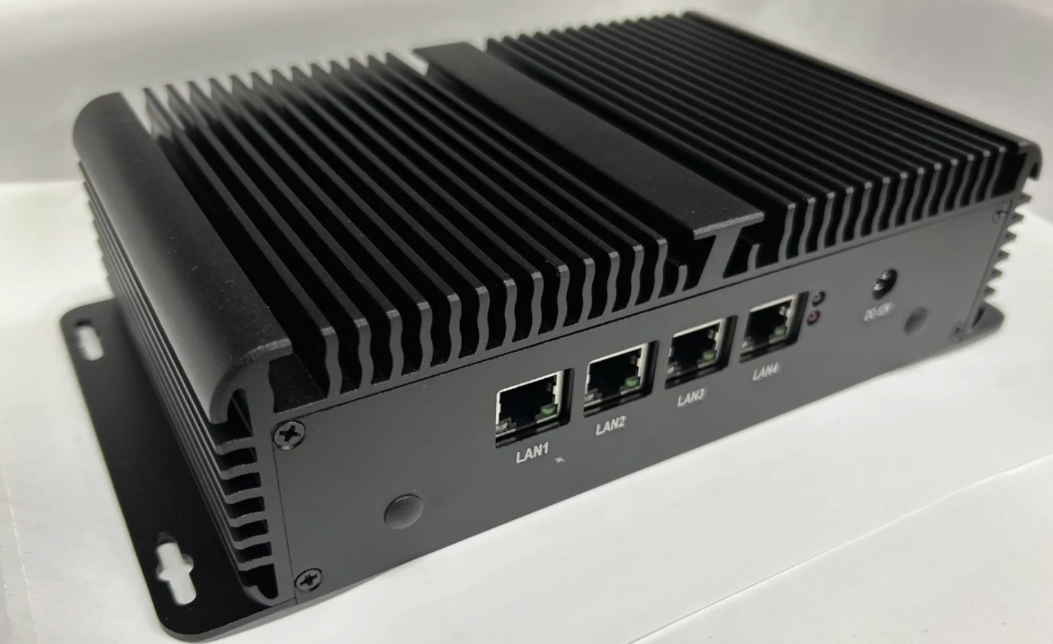 黒い金属筐体の ForceLink BOX。上面は放熱フィン、前面に LAN1〜LAN4 と記された4つのLANポートと DC-12V の電源ジャック、側面に穴あきの取付金具。